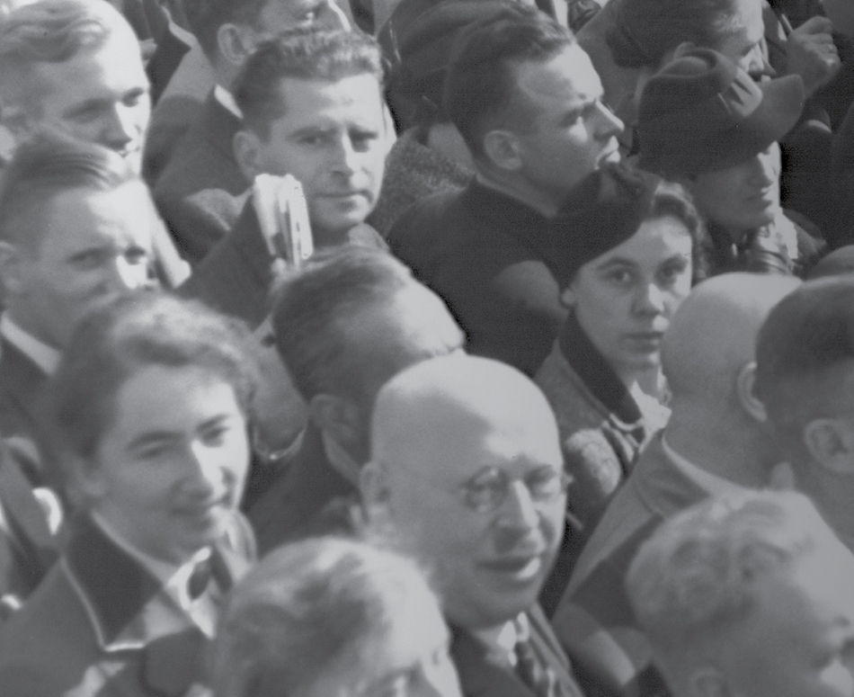 En grupp människor. Några tittar mot kameran men de flesta tittar mot något annat.